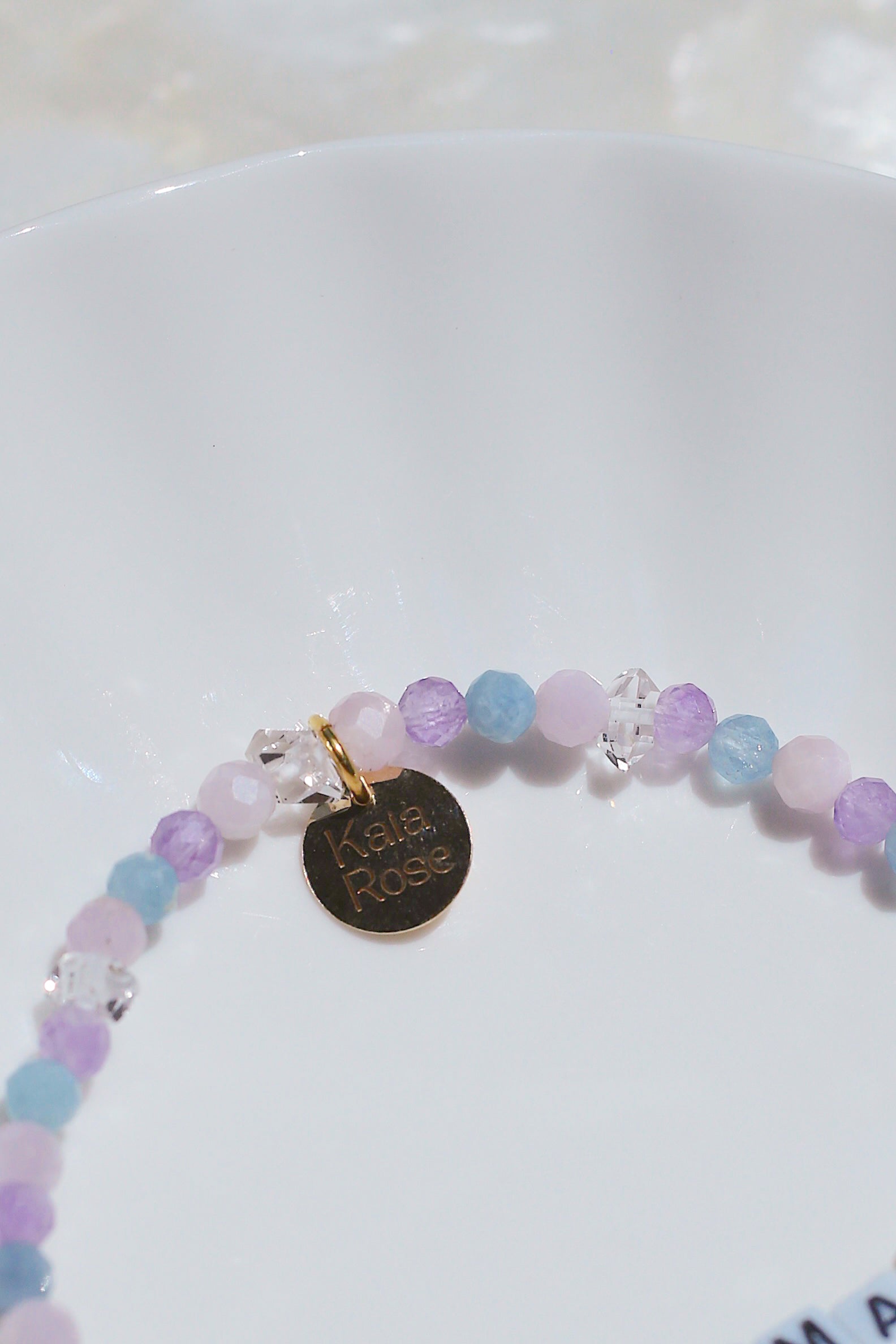 Close-up of Cotton Candy pastel beads and Kaia Rose brand charm on white dish