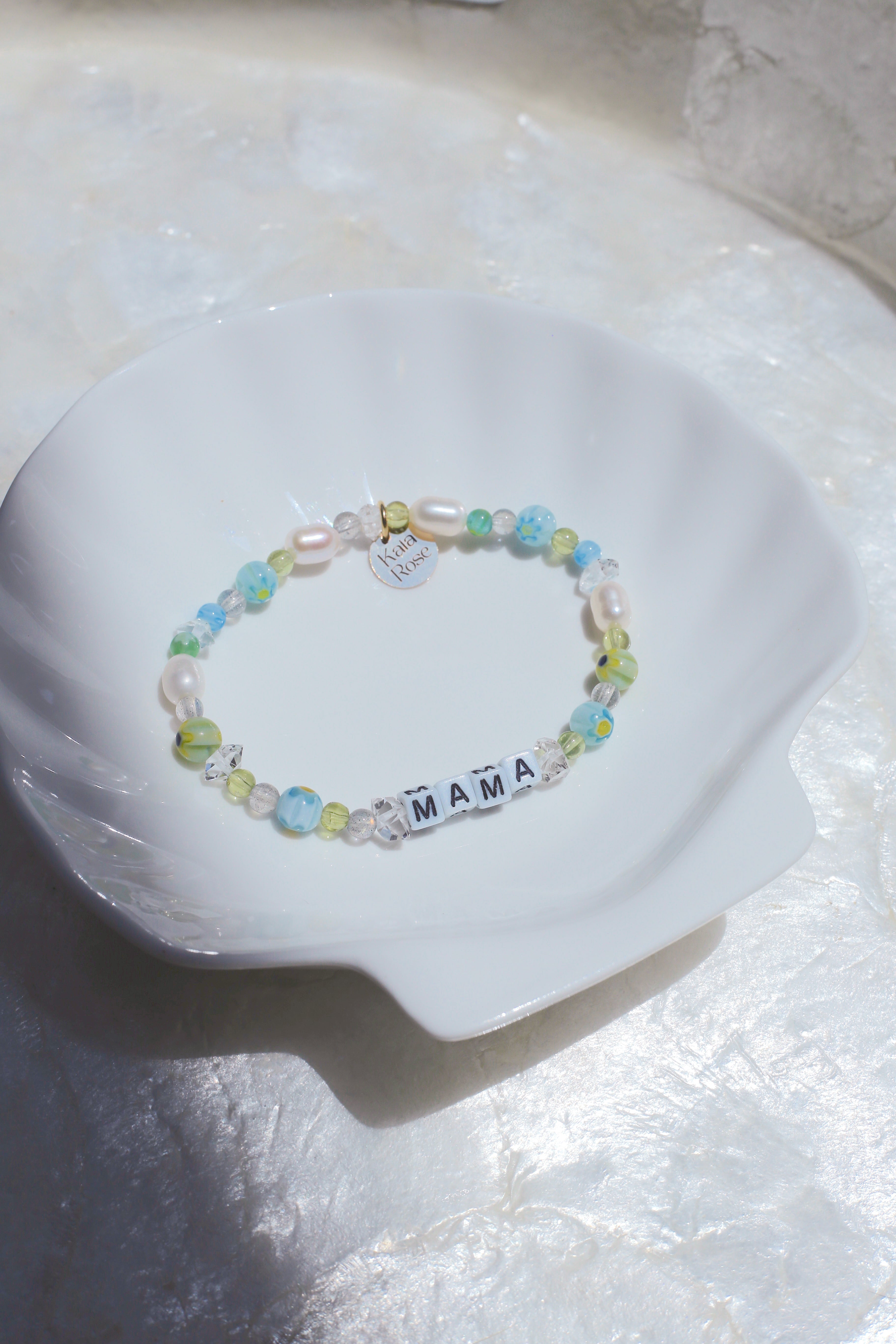 Meraki customizable gemstone bracelet (spelling 'MAMA') on a white dish